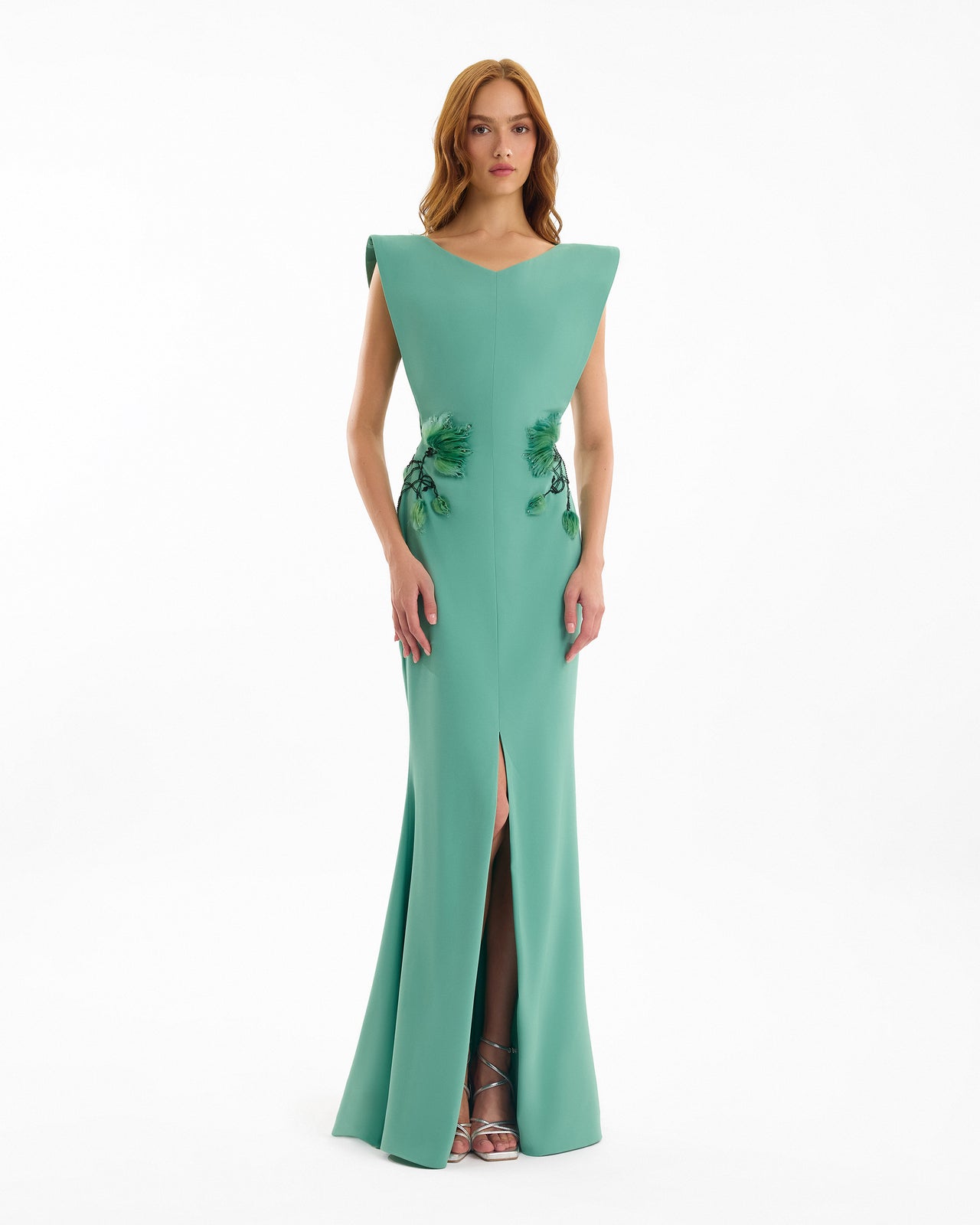 Woman wearing a green evening gown with floral details on a white background