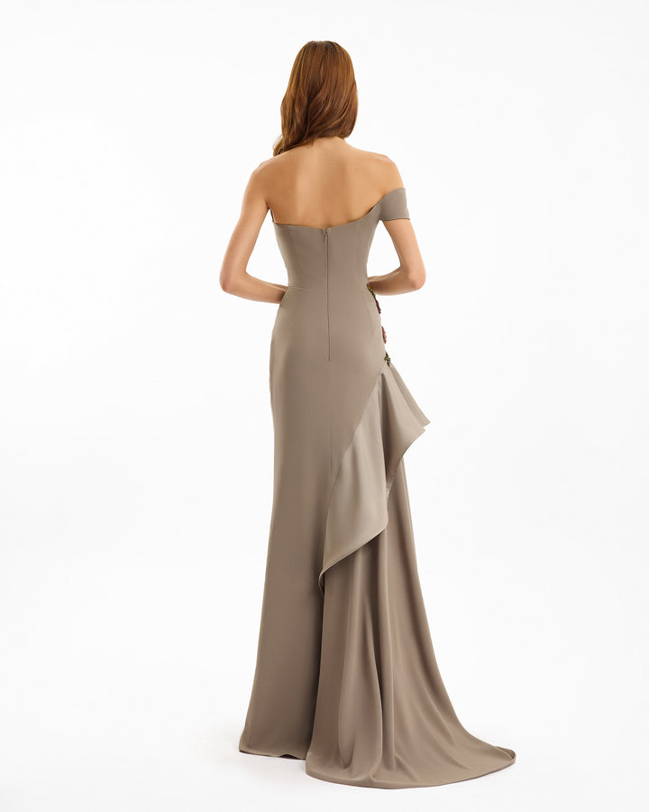 Woman wearing a beige strapless gown with a ruffled skirt on a white background