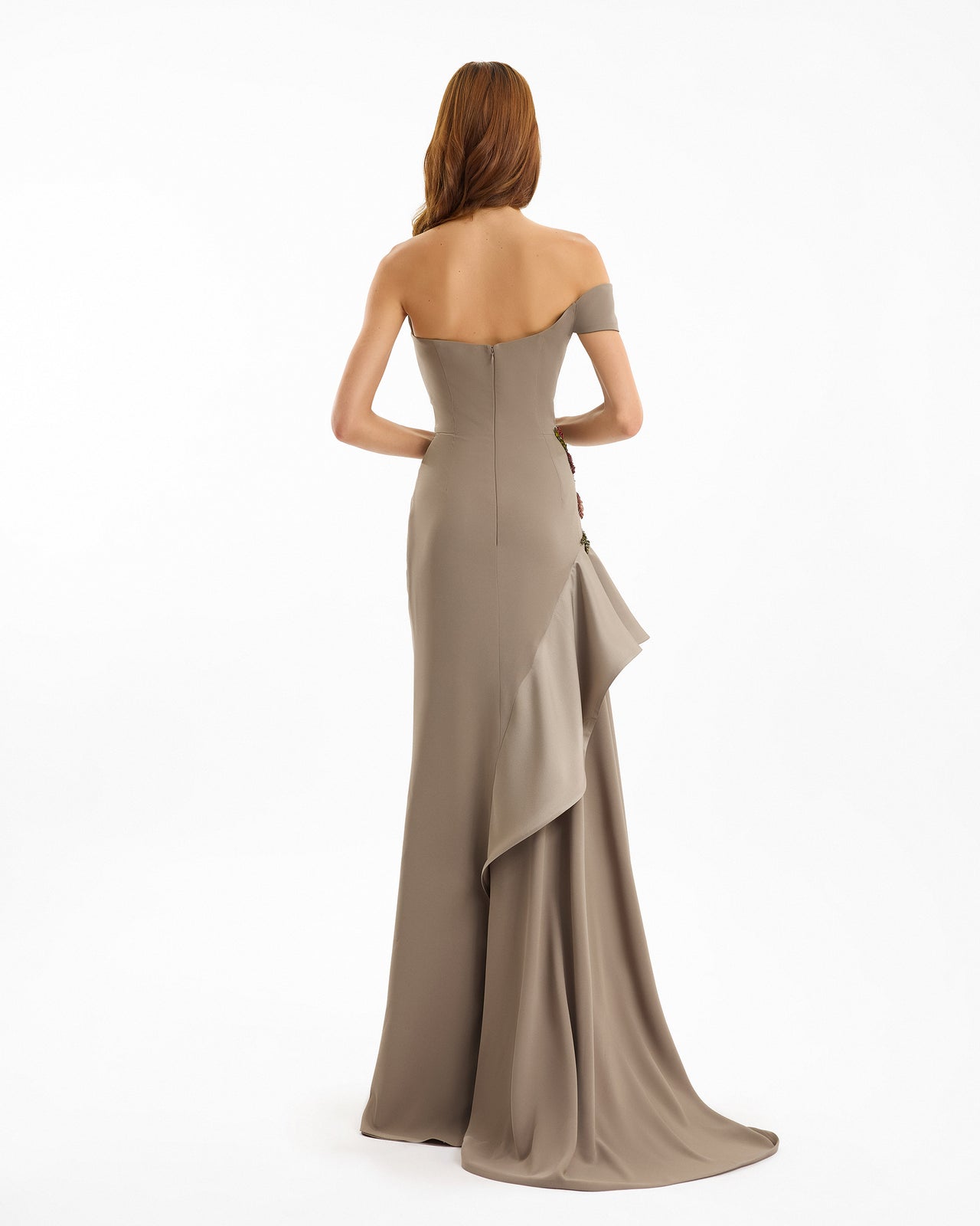 Woman wearing a beige strapless gown with a ruffled skirt on a white background