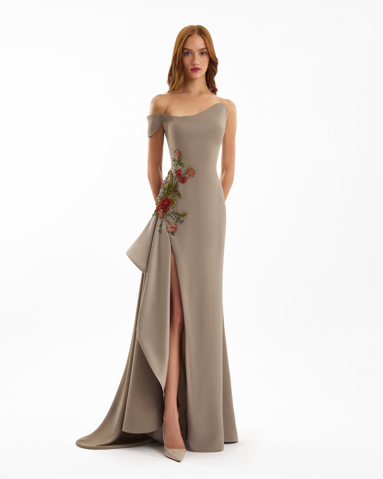 Woman wearing a beige evening gown with floral embroidery on a white background