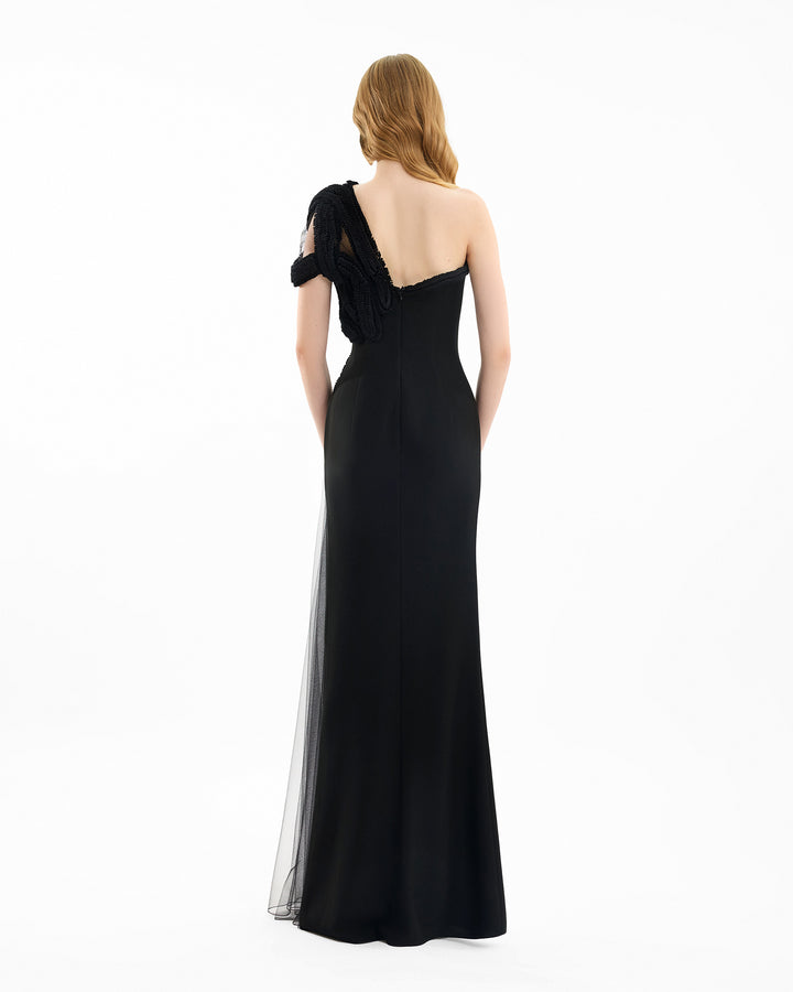 Black evening gown with sheer overlay on a white background