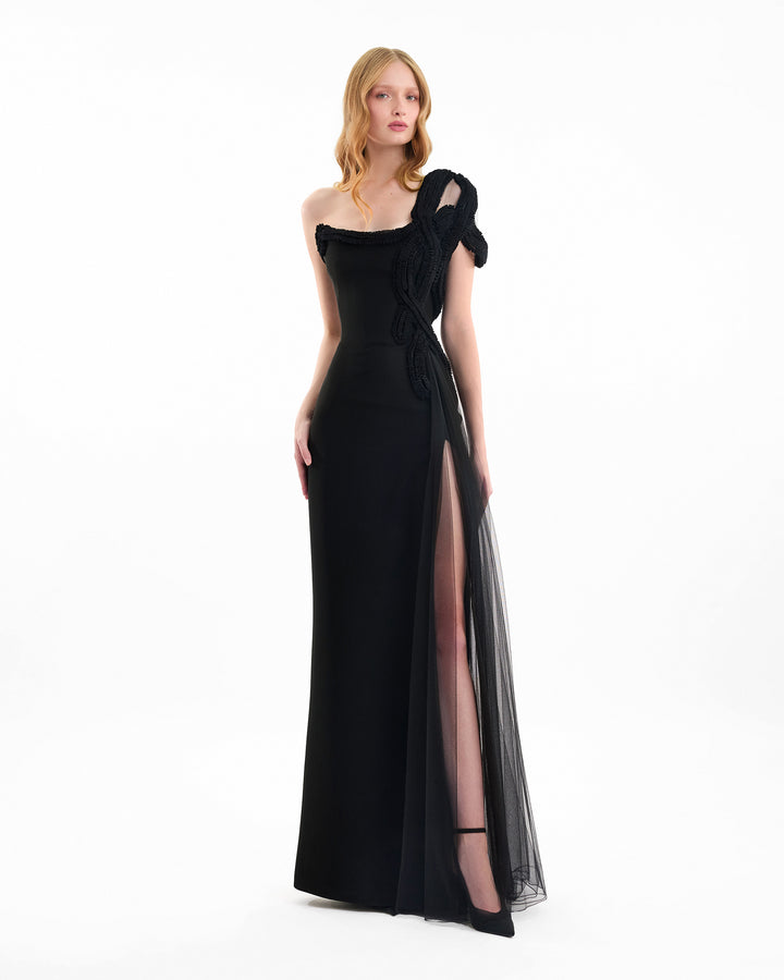 Woman wearing a black evening gown with a sheer side panel on a white background