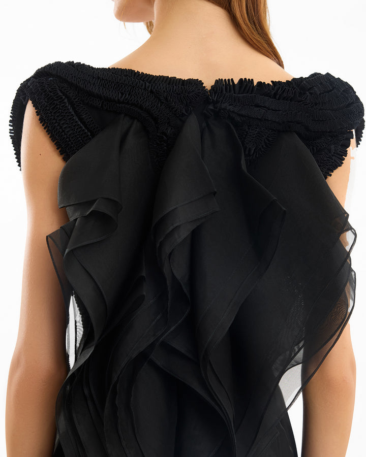 Black ruffled dress with sheer overlay on a white background