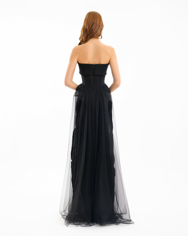 Black strapless gown with sheer overlay on a white background