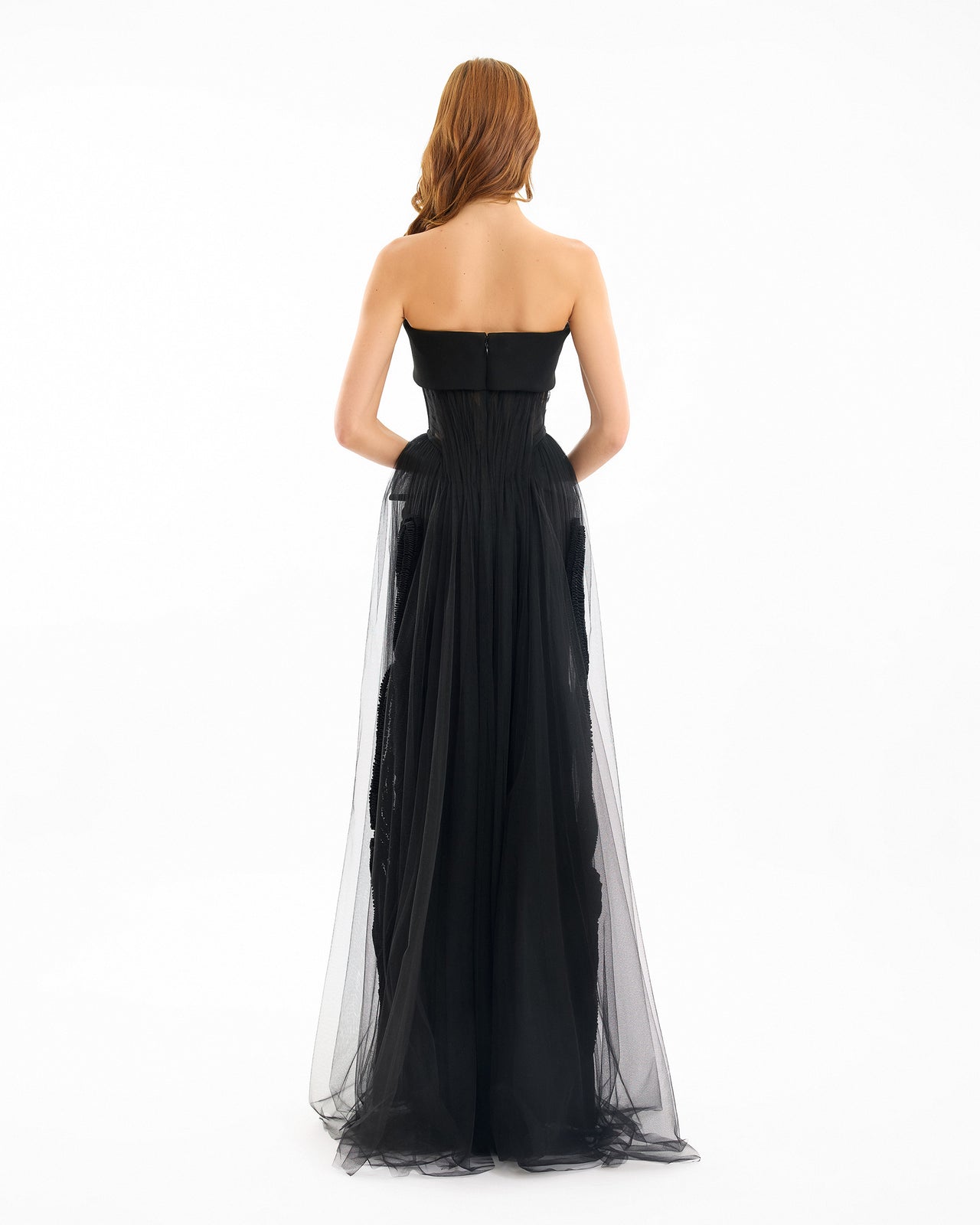 Black strapless gown with sheer overlay on a white background