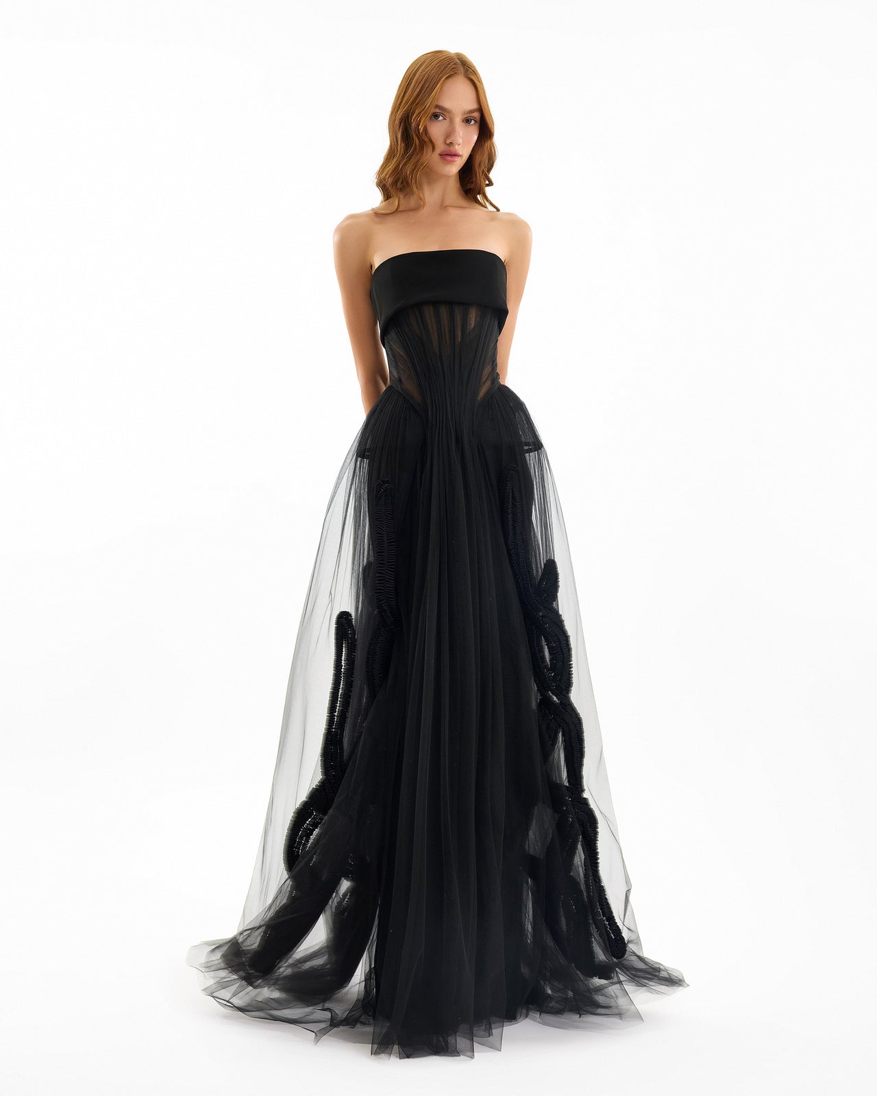 Black strapless gown with sheer overlay on a white background