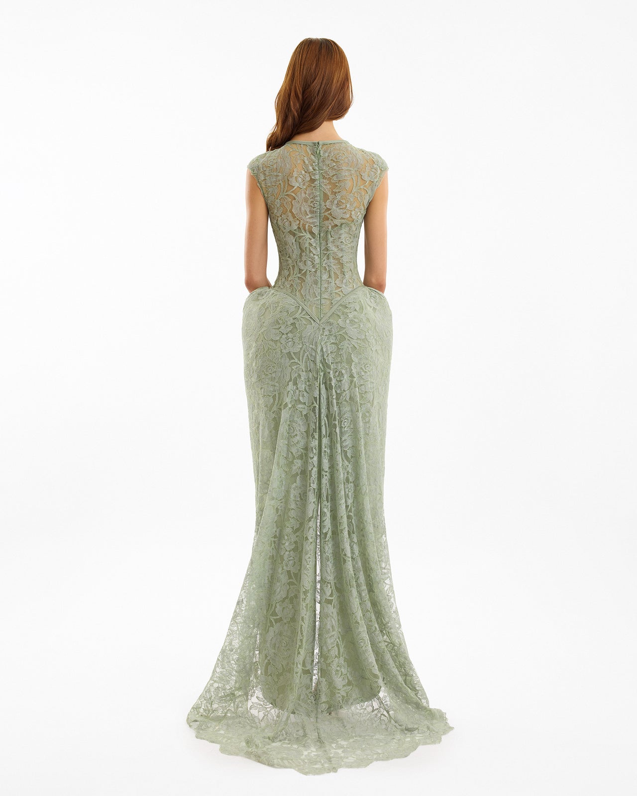 Woman wearing a long, light green lace dress on a white background