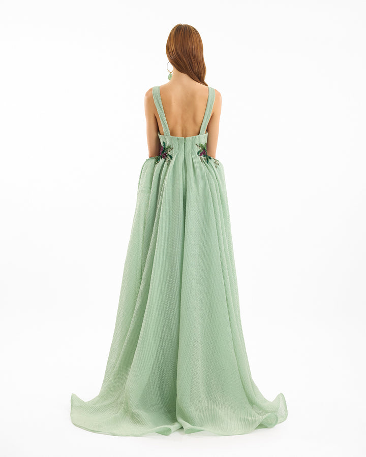 Light green evening gown with thin straps on a white background