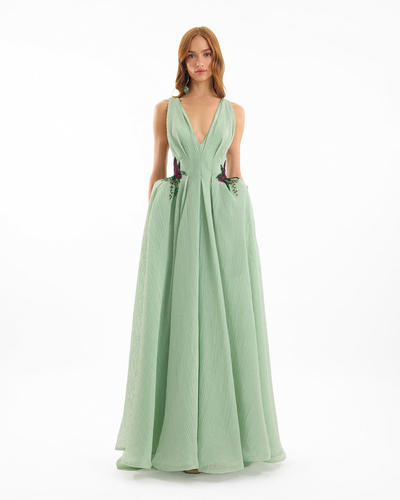 Woman wearing a light green evening gown on a white background