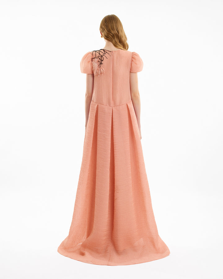 Woman wearing a long pink dress with lace details on a white background