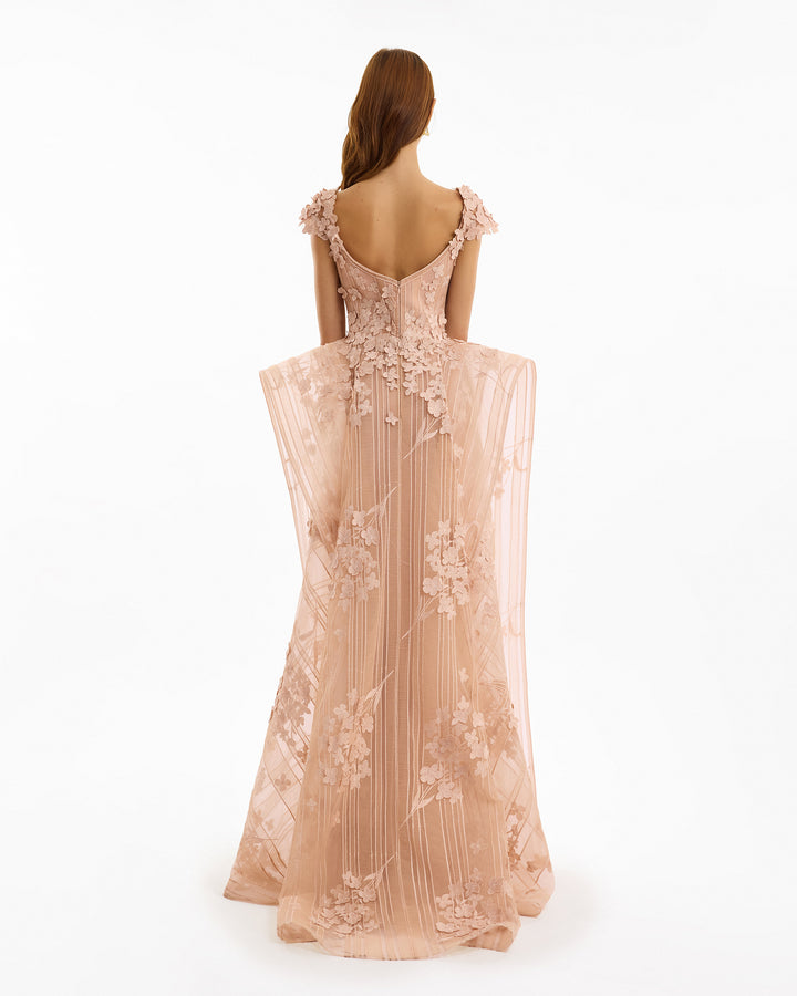 Woman wearing a beige evening gown with floral embroidery on a white background