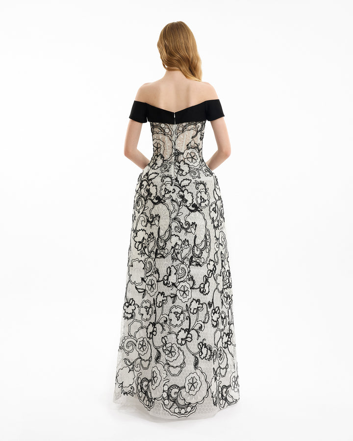 Woman wearing a black and white floral off-shoulder gown on a white background