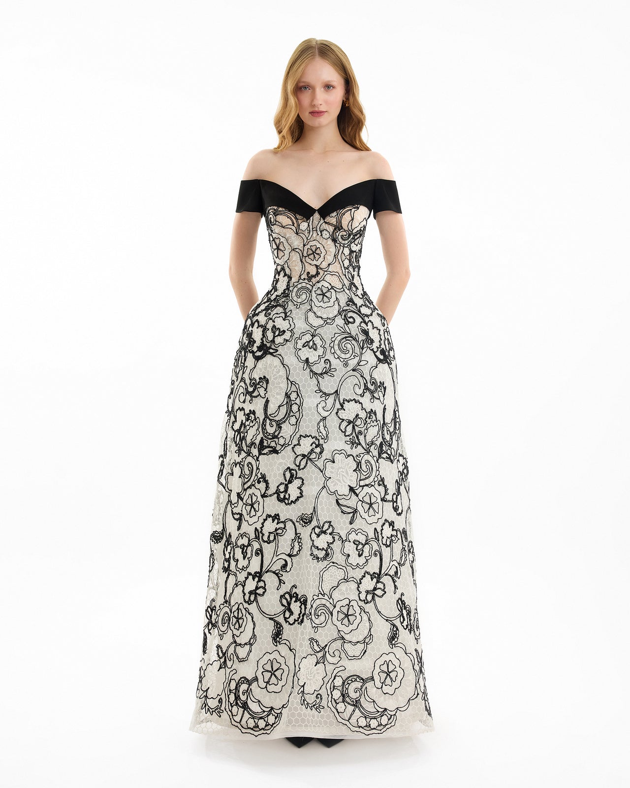 Woman wearing a black and white floral off-shoulder gown on a white background