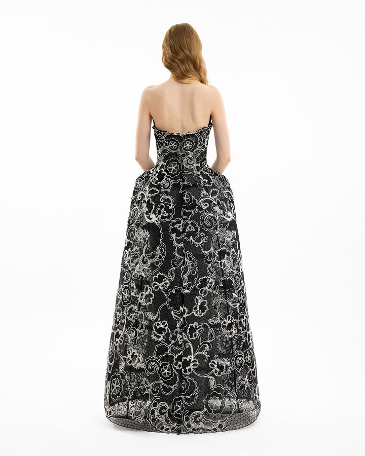 Woman wearing a black and white floral strapless gown on a white background