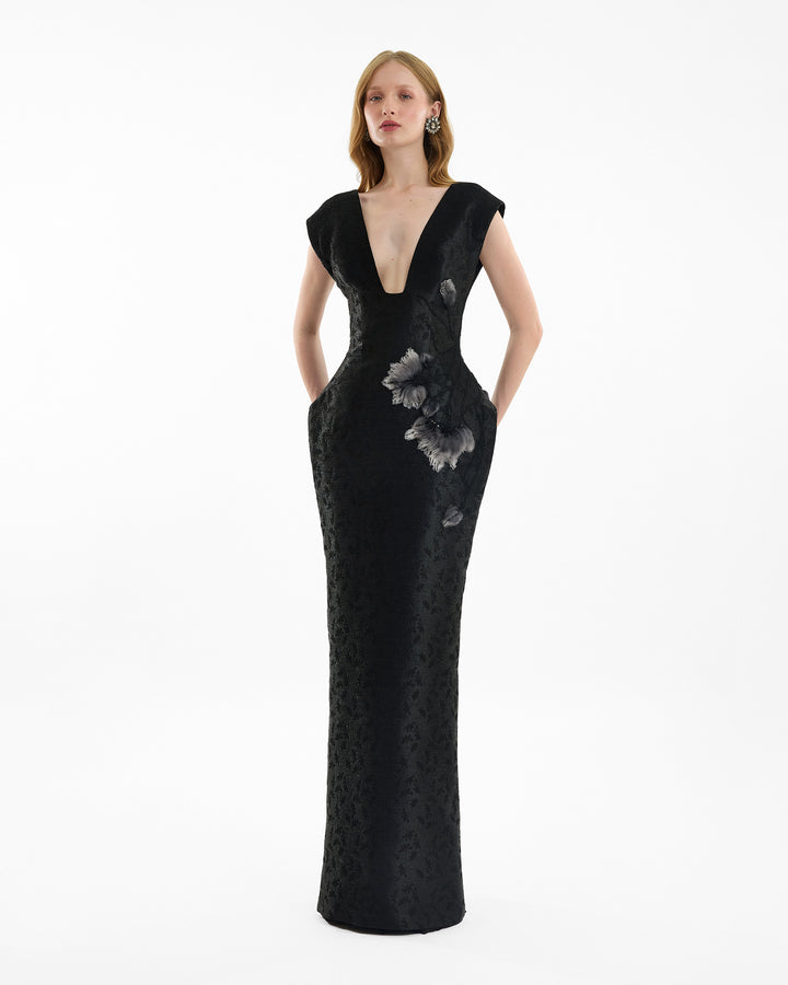 Black evening gown with floral embellishments on a white background