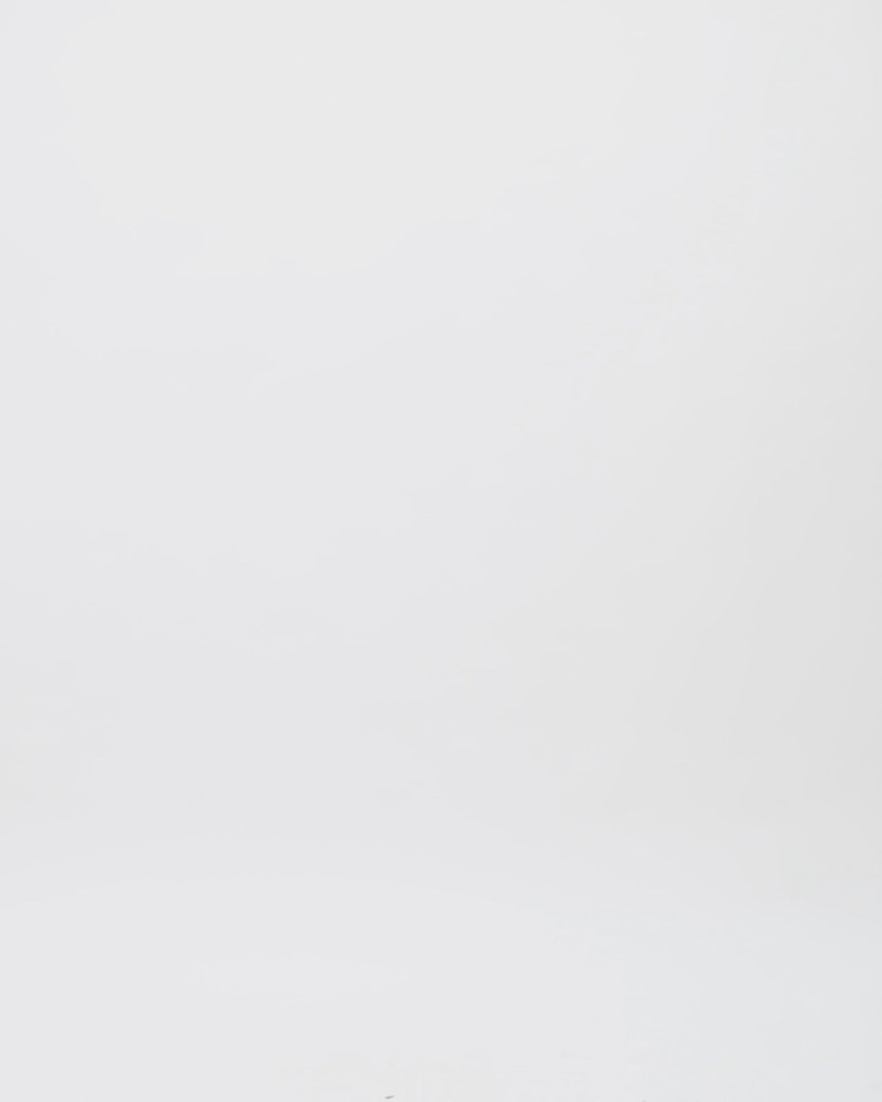 A long black and white evening dress with draped off-the-shoulder sleeves in black crepe fabric and a black and white sequins overlaying a long white skirt.