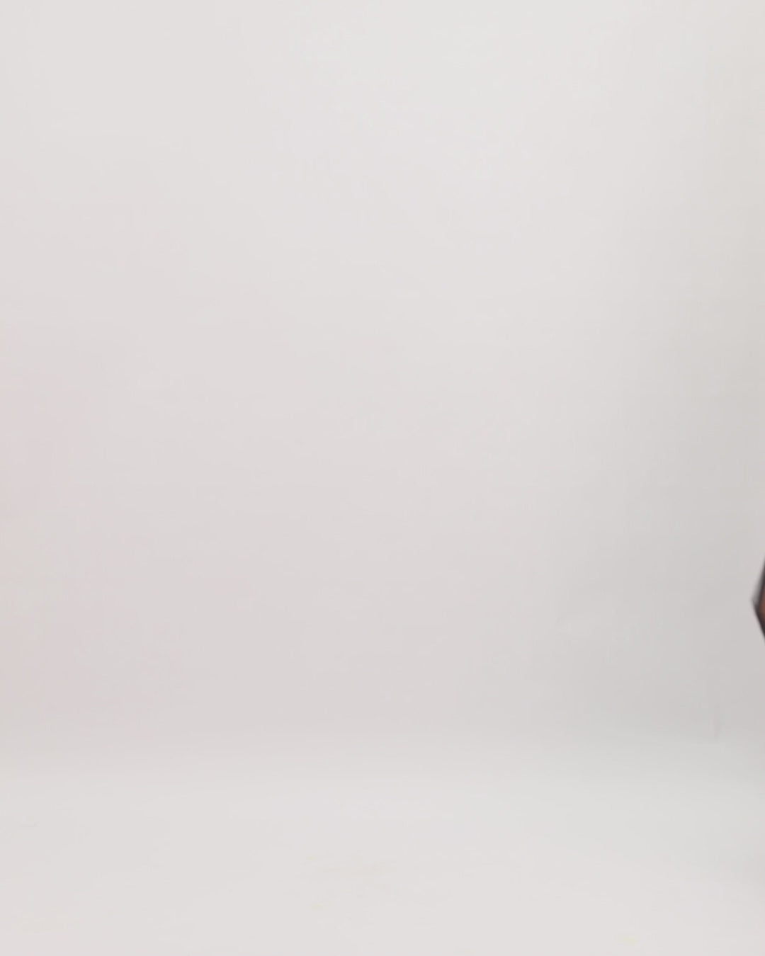 A strapless black evening dress with an asymmetrically draped corset and a tulle skirt with a slit on the side.