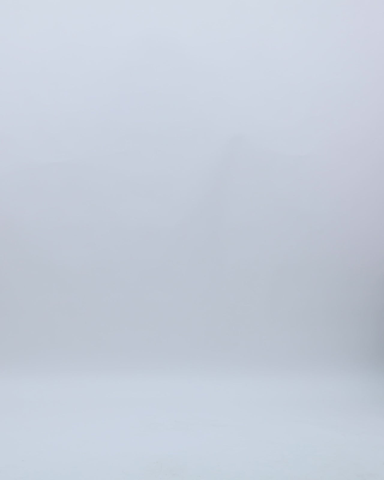 An asymmetrical draped dress in grey metallic jersey with a cape-like floor length sleeve, beadings on the shoulder, a cut-out at the back, and a slit on the side.