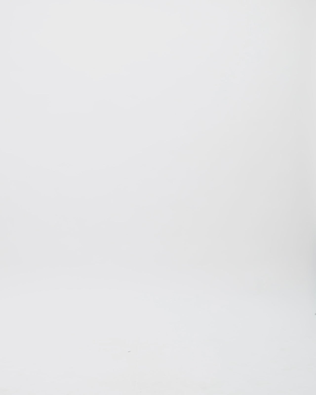 A loose-cut kaftan-style black dotted white tulle dress featuring beadings on the neckline, a draped flower on the shoulder, and a black hemline.