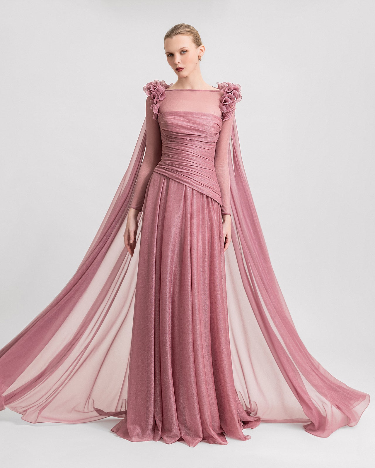 Video of a strapless pink shimmer dress paired with a detachable sheer long-sleeve top featuring floral appliqué on the shoulders, showcasing the full look from multiple angles in motion.