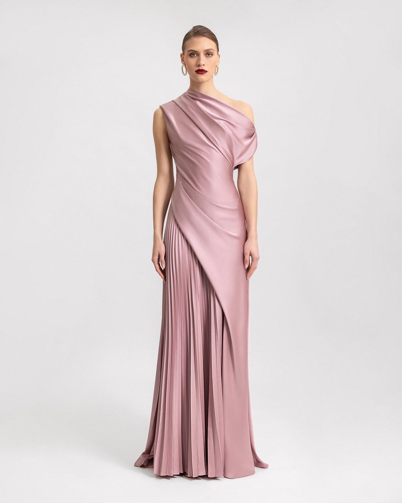 Video of a one-shoulder pink satin dress with draped bodice and pleated skirt, showcasing the dress's fluid movement and elegant silhouette from multiple angles.