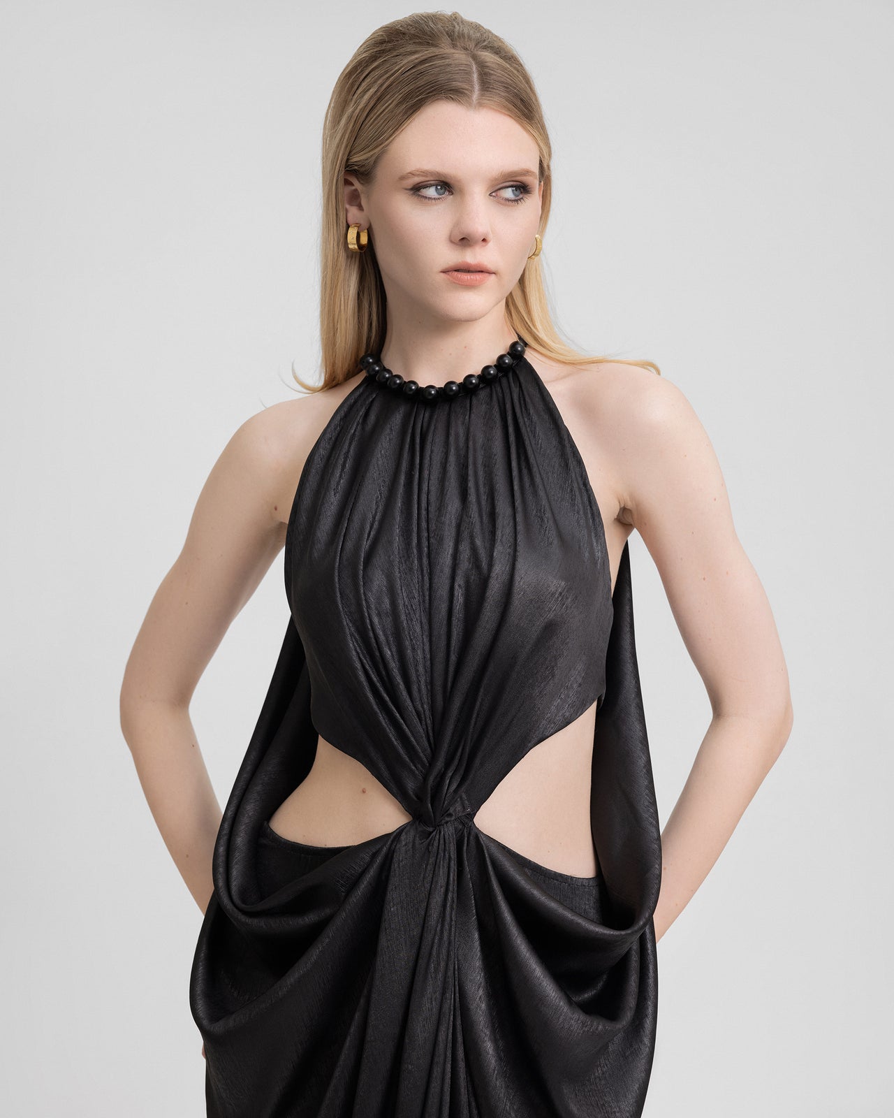 Video showcasing a long black lamé georgette dress with an embellished halter neckline, side cut-outs, and a front slit. The model walks and turns to display the fluid draping, back view, and shimmering fabric movement.