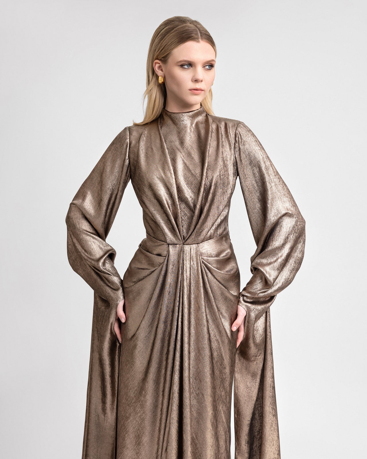 Video of a metallic lamé georgette gown with waist draping, long ruffled sleeves, and a 120 cm hemline, capturing its shimmer, fluid movement, and elegant back keyhole detail for eveningwear.