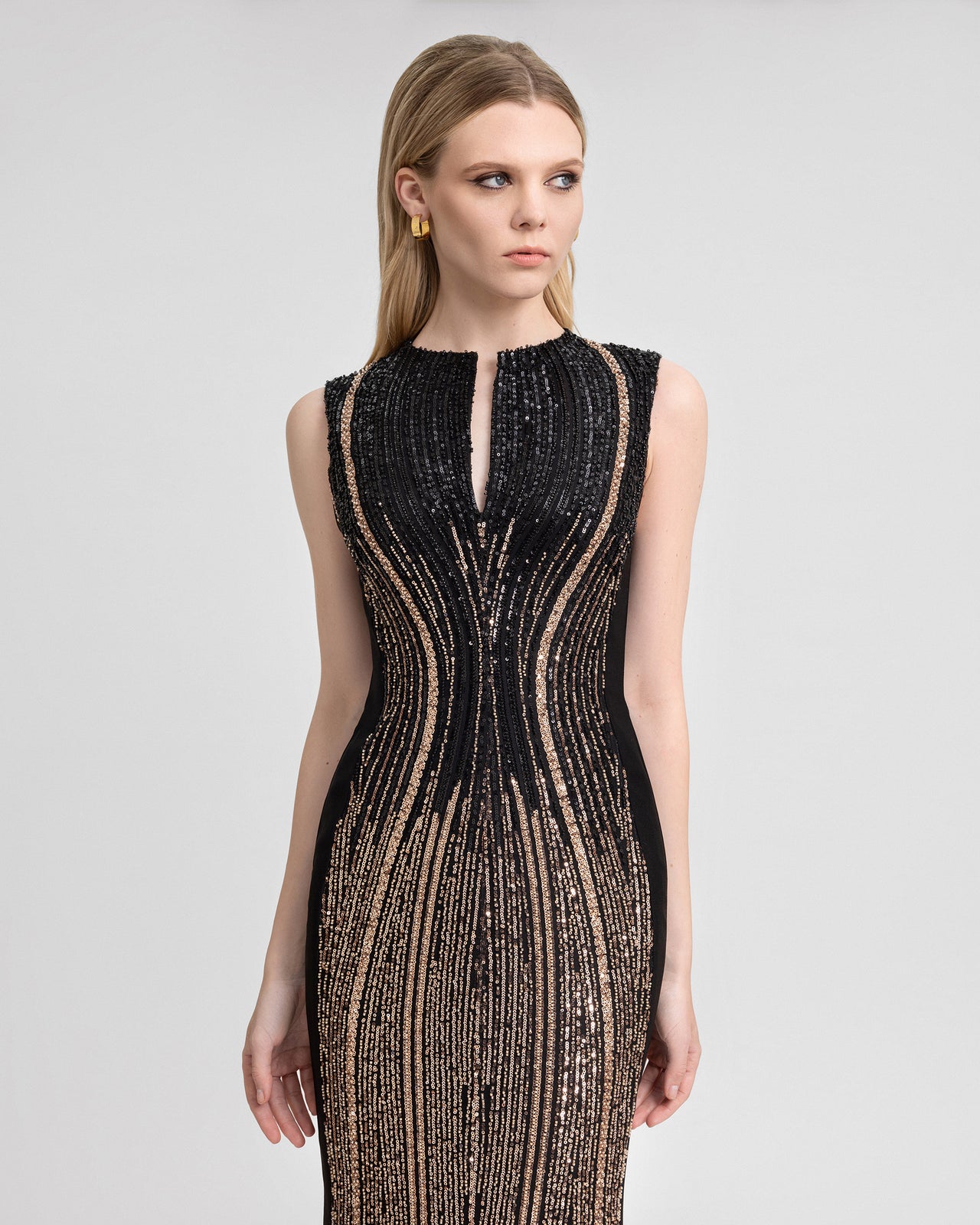 Video of a slim-cut crepe and beaded tulle gown with a structured neckline, chest cut-out, and 120 cm hemline, showcasing shimmering sequin detailing and a back slit in motion for formal eveningwear appeal.