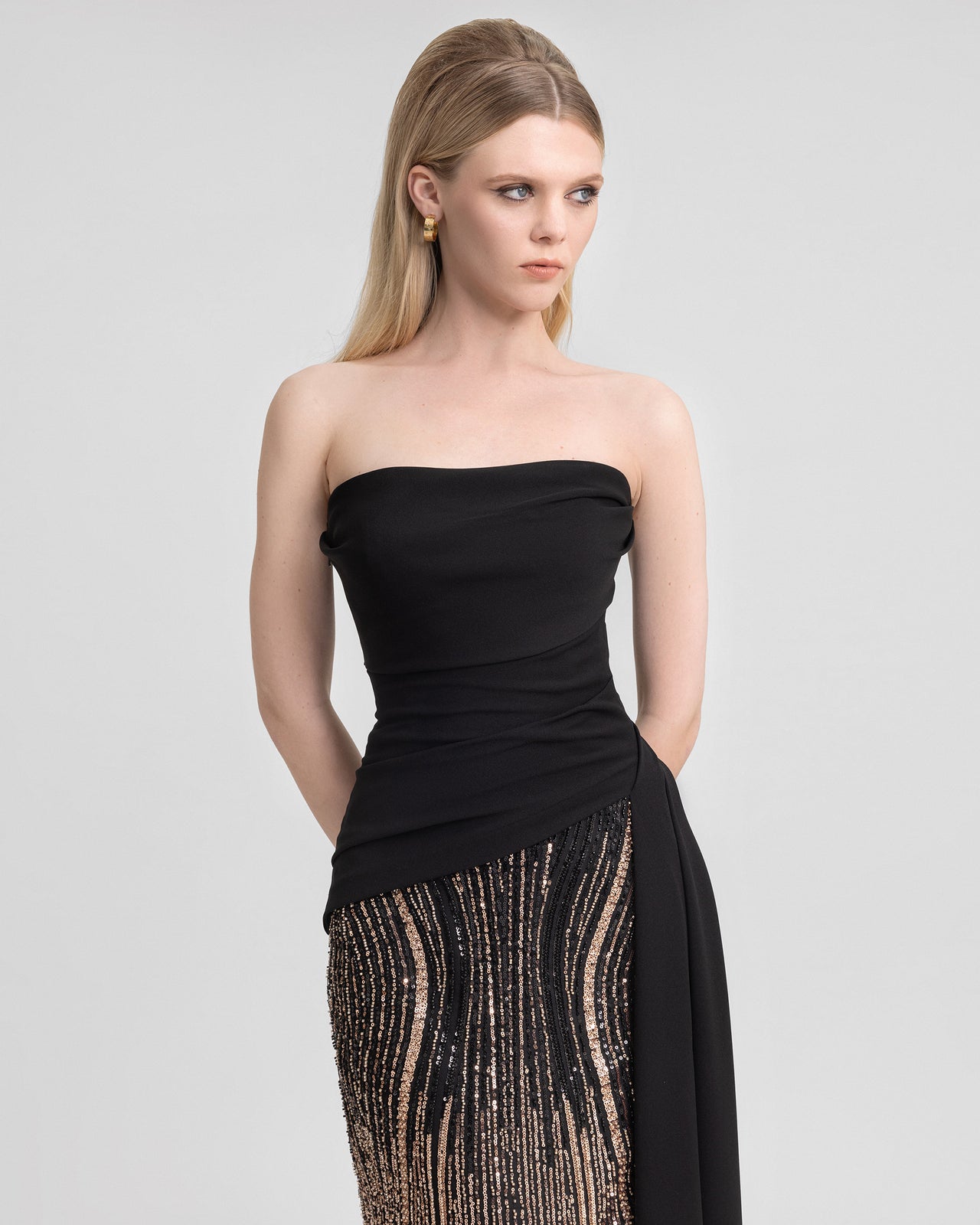 Video of a strapless draped dress with a black crepe bodice, one-sided overskirt, and a 120 cm beaded tulle skirt, capturing the contrast of textures and sequin shimmer in motion for elegant eveningwear.