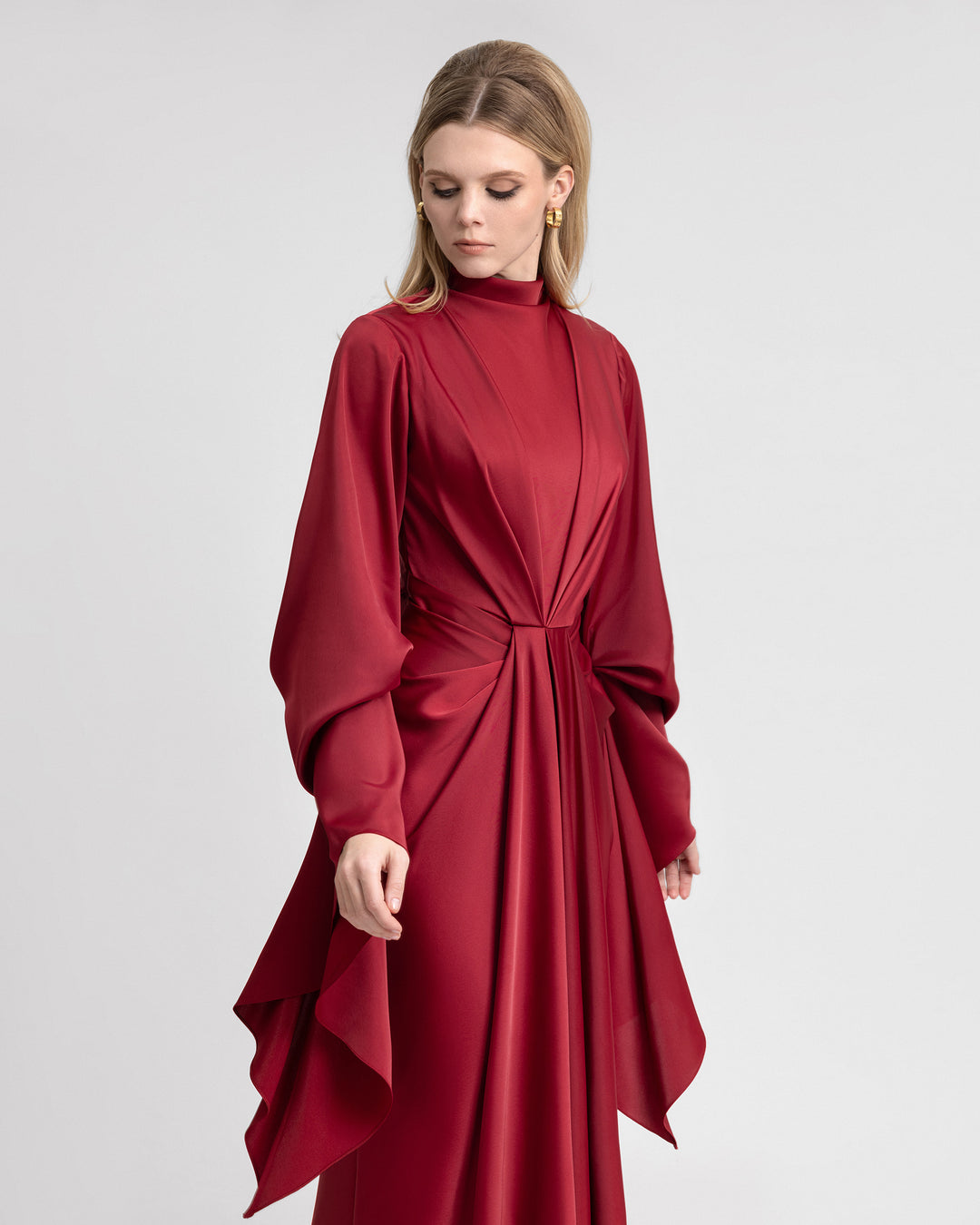 Video of a model showcasing a long satin dress with elegant waistline draping and dramatic long ruffled sleeves. The gown flows gracefully as the model moves, highlighting the luxurious texture and structured design of the satin fabric.