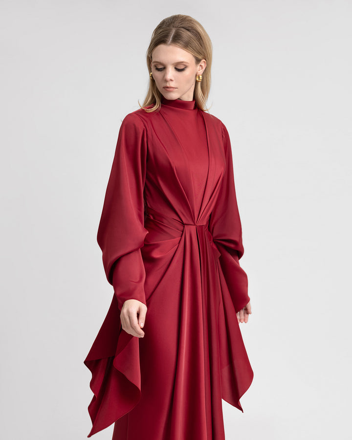 Video of a model showcasing a long satin dress with elegant waistline draping and dramatic long ruffled sleeves. The gown flows gracefully as the model moves, highlighting the luxurious texture and structured design of the satin fabric.