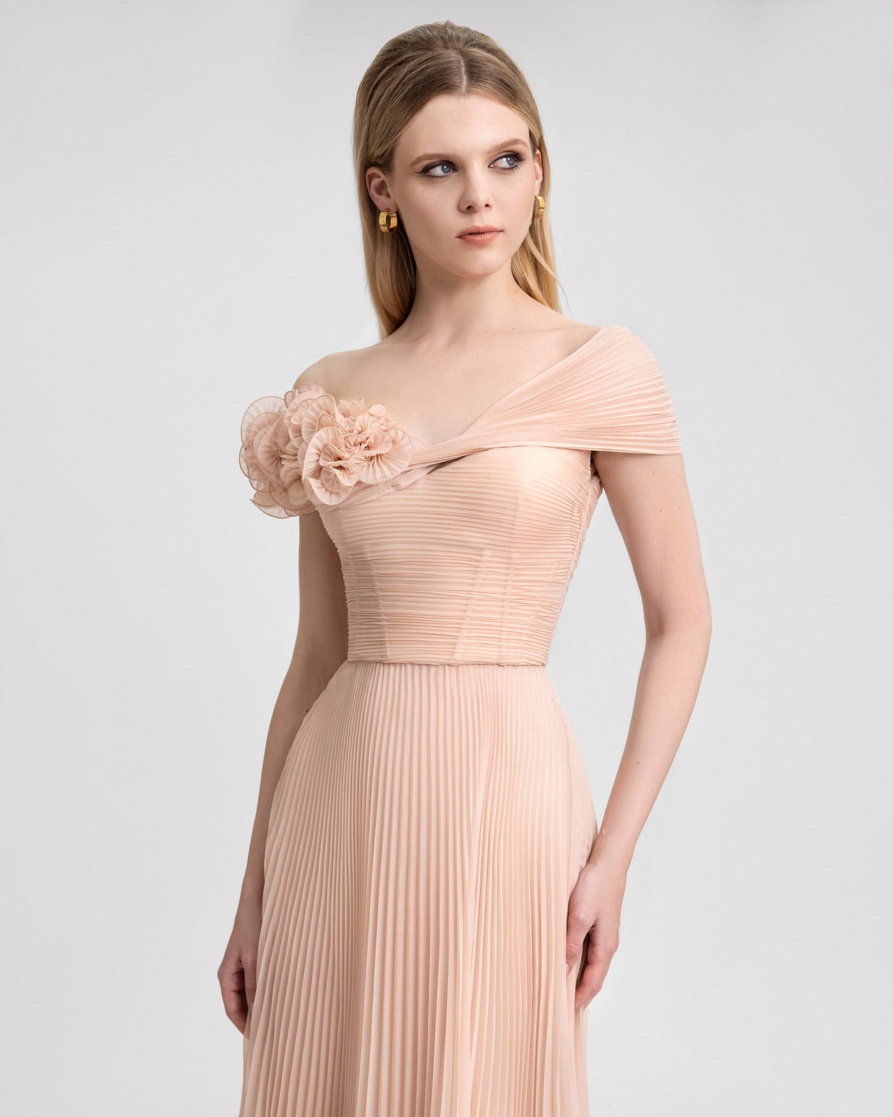 Video of a blush chiffon corset dress with floral asymmetrical neckline and pleated skirt, shown from multiple angles for formalwear styling.