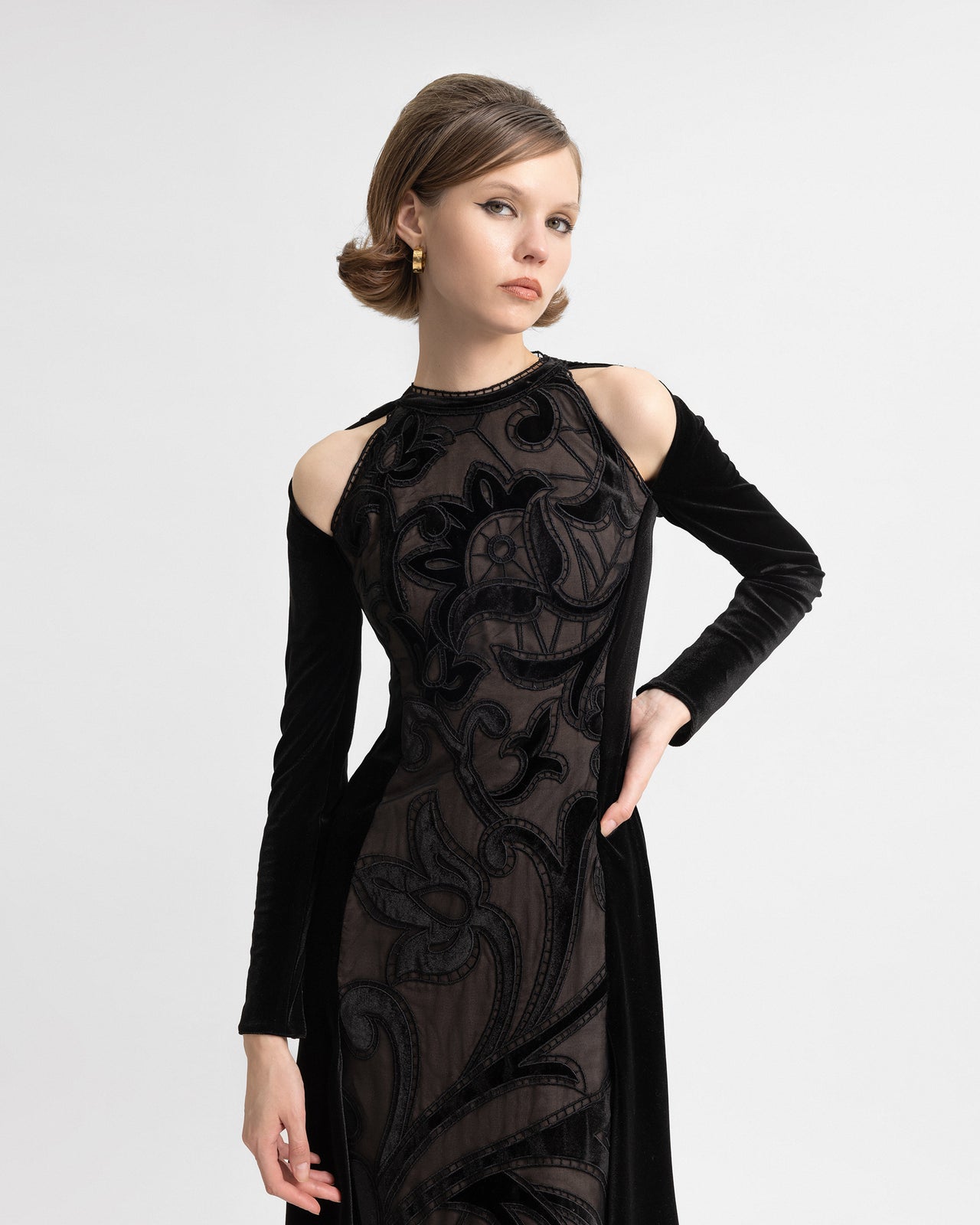 Video showing a model wearing a black velvet gown with shoulder cut-outs, floral embroidery, long sleeves, and a flowing train, captured from multiple angles to highlight movement and detailing.