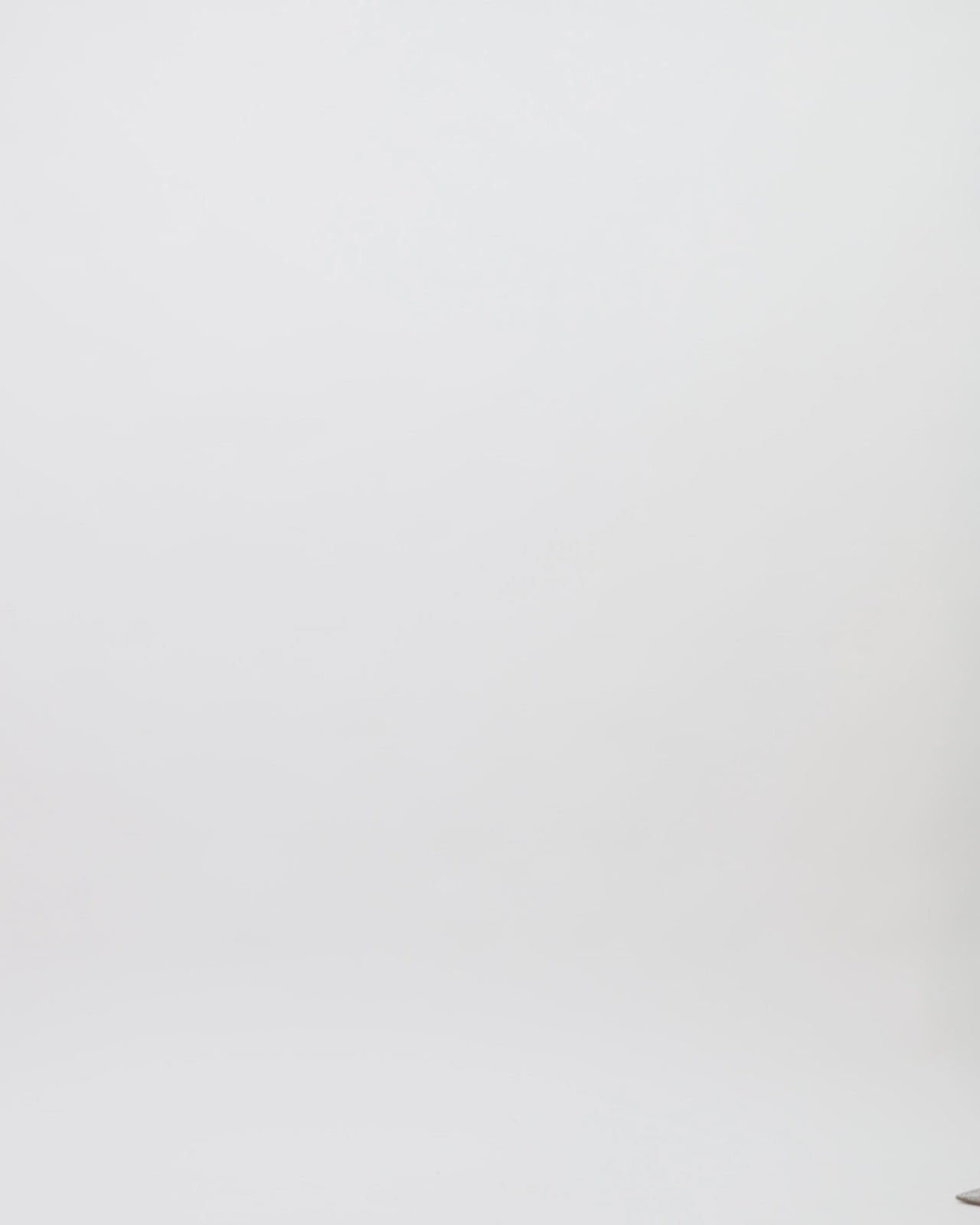 A one-shoulder draped evening dress in caramel color satin with floral embellishments on the neckline and an open slit on the side.