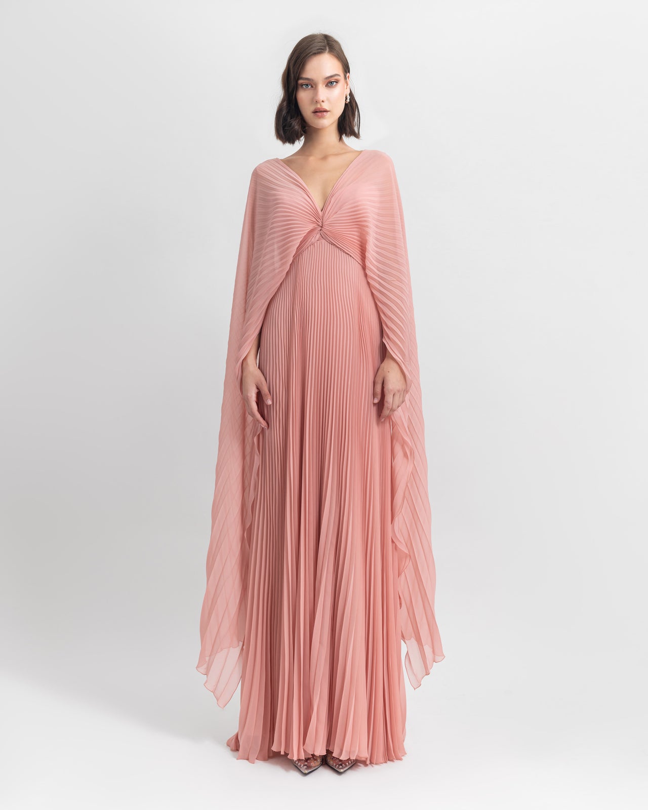 A V-neckline fully pleated flared chiffon dress in pink with draping details.